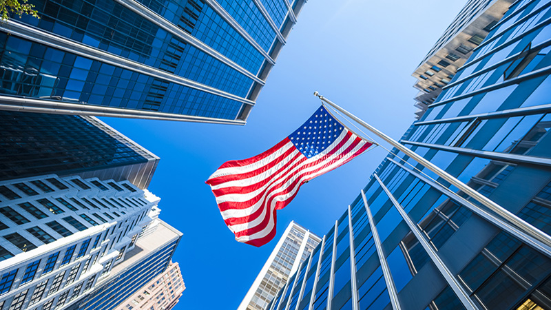 USA flag and contemporary glass architecture of Financial District, New York City, USA.